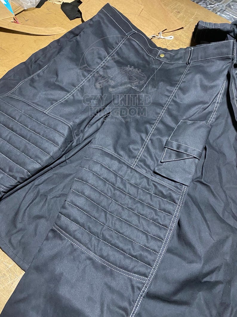 May include: Black pants with white stitching and a cargo pocket. The pants have a quilted design on the front and the text "CZY UNITED KINGDOM" printed on the front. The pants are made of a durable material.