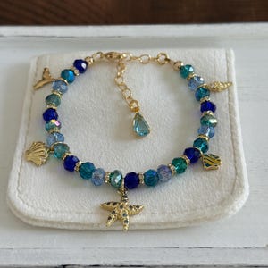 Ocean theme multi charm with sparkly mix blue glass crystal beads 14K gold filled bracelet; dolphin tail, shells, starfish, marine charms