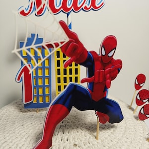 Puede incluir: Un adorno para tarta con tem&aacute;tica de Spider-Man en rojo, azul y blanco, con el nombre "Max" en letras rojas. El dise&ntilde;o incluye un paisaje urbano, el n&uacute;mero "1" y varios recortes de caras de Spider-Man. La figura principal es Spider-Man en una pose din&aacute;mica.