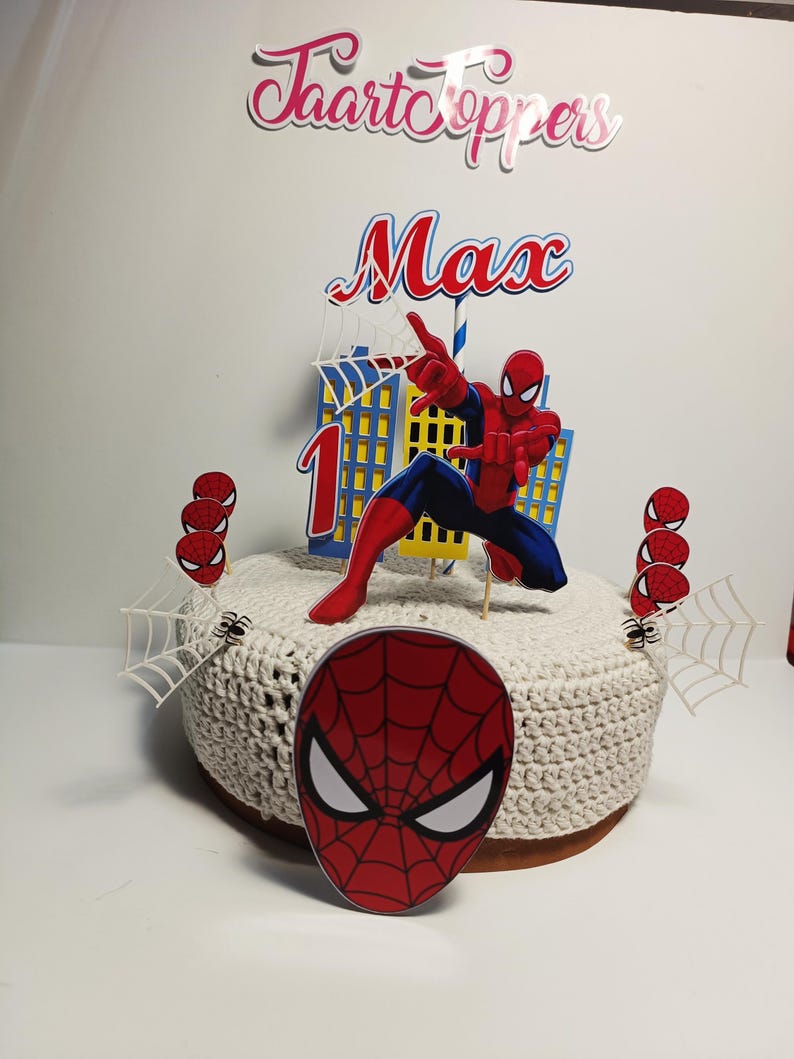 Puede incluir: Adorno para tarta con una figura de Spider-Man rojo y azul, un edificio y el nombre "Max" con el n&uacute;mero "1". El adorno incluye telara&ntilde;as y detalles de ara&ntilde;as, ideal para una celebraci&oacute;n de cumplea&ntilde;os.