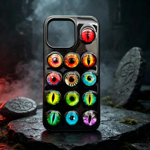 May include: A black smartphone case featuring a grid of thirteen raised, glossy, realistic eye designs in various colors including red, orange, yellow, green, blue, and purple, each with a distinct pupil shape set against a dark background.