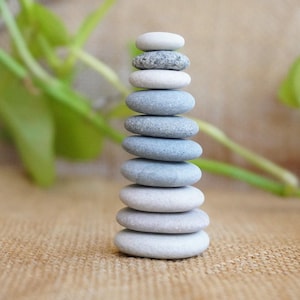 May include: A stack of smooth, gray and white stones balanced on top of each other. The stones are arranged in a pyramid shape, with the largest stone at the bottom and the smallest stone at the top.