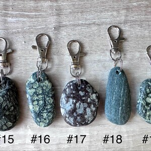 K&ouml;nnte beinhalten: F&uuml;nf Schl&uuml;sselanh&auml;nger mit Natursteinen in einzigartigen Texturen und Farben, jeweils an einem silberfarbenen Metallkarabiner befestigt. Die Steine sind mit #15, #16, #17, #18 und #19 beschriftet und zeigen verschiedene Gr&uuml;n-, Braun- und Graut&ouml;ne.