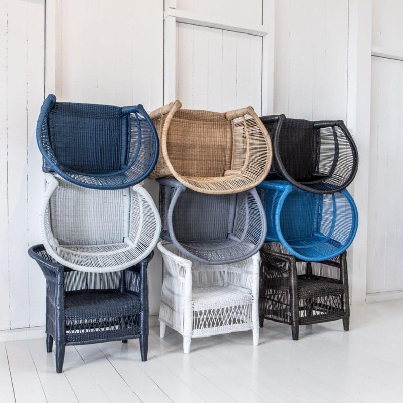 May include: A collection of woven wicker chairs in various colors, including navy blue, tan, black, light gray, blue, white, and dark gray. The chairs have a unique design with a rounded back and armrests, suitable for indoor or outdoor use.