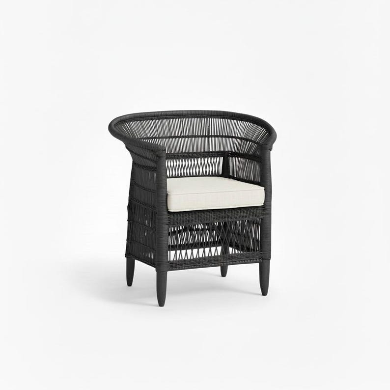 May include: Black wicker armchair with a curved back and a cream-colored cushion. The chair has a woven design and four short legs. This outdoor or indoor chair is a stylish seating option.