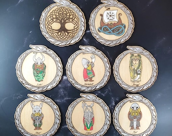 May include: Nine wooden coasters with intricate designs featuring Norse mythology figures and symbols. Each coaster has a silver-colored border and a different image, including a tree of life, a ship, Loki, Heimdall, Frigg, Thor, Odin, and Tyr.