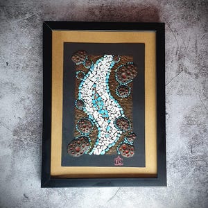 May include: A framed mosaic artwork featuring a white and blue abstract design with brown and red accents. The artwork is set against a black background and framed in black.