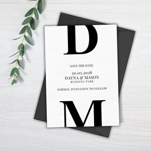 Op de afbeelding: Een witte save-the-date kaart met zwarte tekst. De kaart heeft de letters "D" en "M" in een groot, vet lettertype. De tekst luidt "Save the Date", "20.05.2028", "Dayna & Mason", "Rudding Park" en "Formal Invitation to Follow".