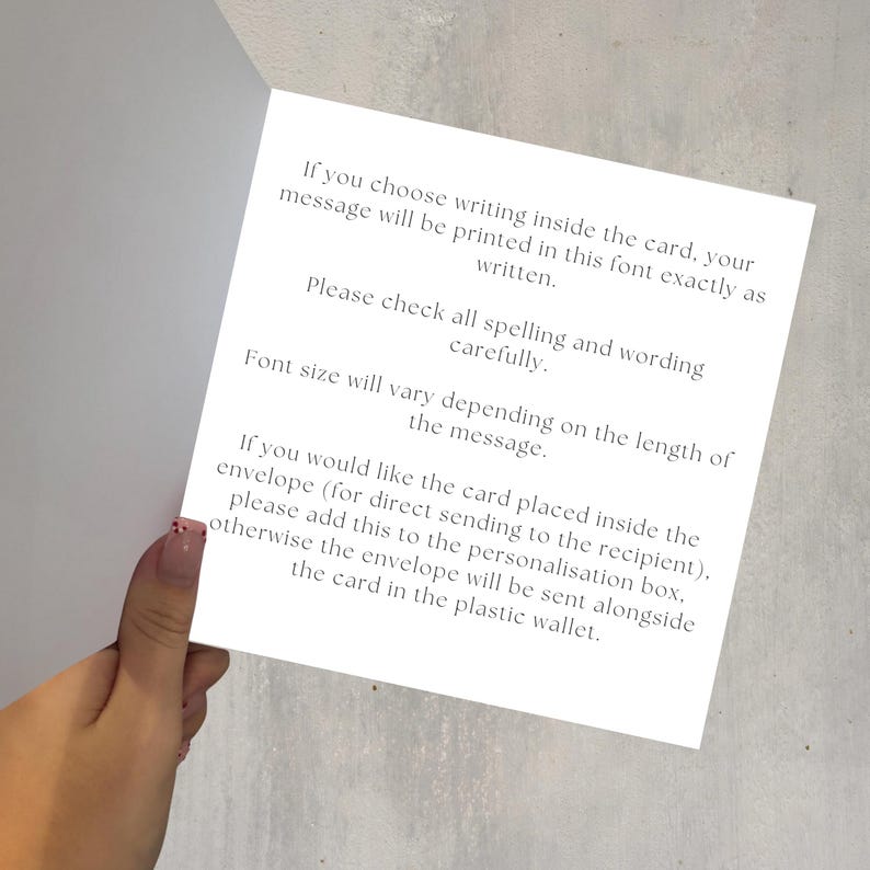 May include: A white card with printed text, held by a hand. The text provides instructions on writing a message inside the card, including checking spelling and wording. It also mentions envelope placement and font size.