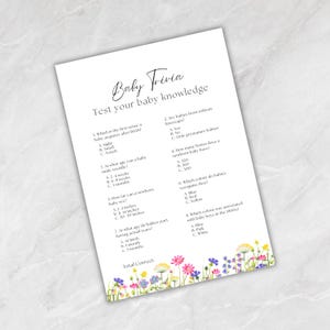 May include: A white sheet with baby trivia questions and answers. The text reads "Baby Trivia" and "Test your baby knowledge". The sheet is decorated with a floral border in various colours.