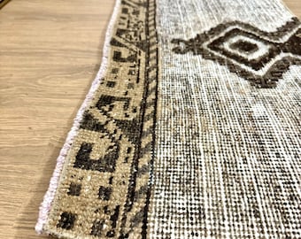 May include: A brown and white patterned rug with a pink border. The rug has a geometric design and is made of woven fibres.