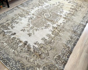 May include: A vintage rug with a floral pattern in shades of brown and white. The rug has a distressed look and is made of a soft, woven material.