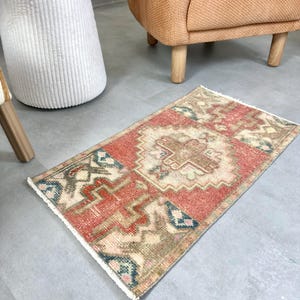 May include: A white ceramic mug with a black handle and the text "But First, Coffee" in a bold, black font. The mug is set against a blurred background, suggesting a cozy setting.