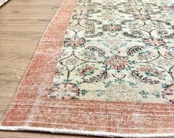May include: A vintage rug with a floral pattern in shades of cream, green, and pink. The rug has a peach-coloured border.
