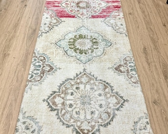 May include: A vintage runner rug with a cream background and intricate floral patterns in shades of brown, green, and pink. The rug has a faded, distressed look, adding to its vintage charm.