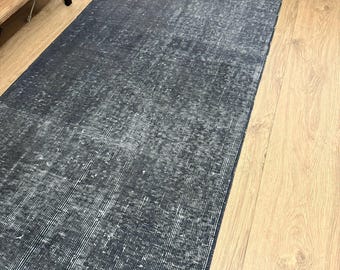 May include: A dark grey distressed rug with a subtle pattern. The rug is laid out on a wooden floor.