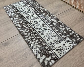 May include: A black and white runner rug with a geometric pattern. The rug has a faded look and is made of a soft, woven material.