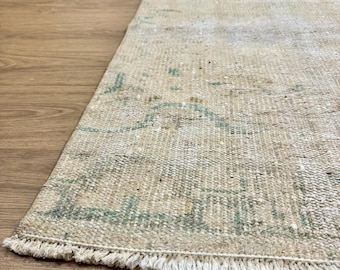 May include: A vintage off-white runner rug with a faded green pattern and frayed edges.