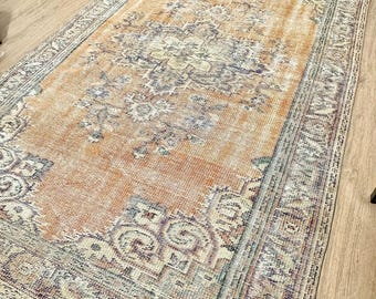 May include: A vintage-style rug with a faded orange and brown colour scheme. The rug has a floral pattern with a central medallion and a border.