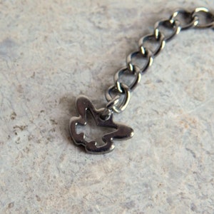 May include: A silver chain with a small, open-work bird charm attached.