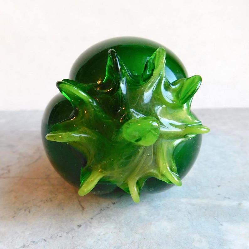 May include: A green glass sculpture of a stylised fruit with a spiky, textured surface.