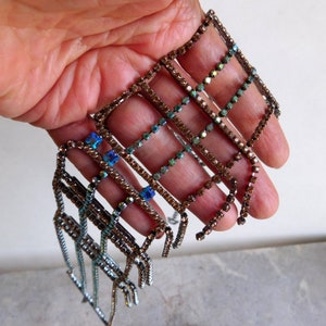 May include: A set of seven rhinestone trim pieces in a variety of shades of brown and blue. The trim is made of small square rhinestones arranged in a grid pattern.