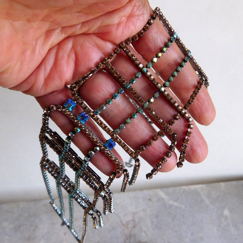 May include: A set of seven rhinestone trim pieces in a variety of shades of brown and blue. The trim is made of small square rhinestones arranged in a grid pattern.