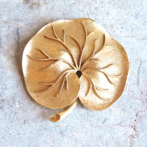 Könnte beinhalten: Ein Set aus drei Keramikbechern mit gesprenkelter, matter Oberfläche. Die Becher sind in den Farben Creme, Hellgrau und Dunkelgrau gehalten. Jeder Becher hat ein schlichtes, minimalistisches Design, ideal für Kaffee oder Tee.