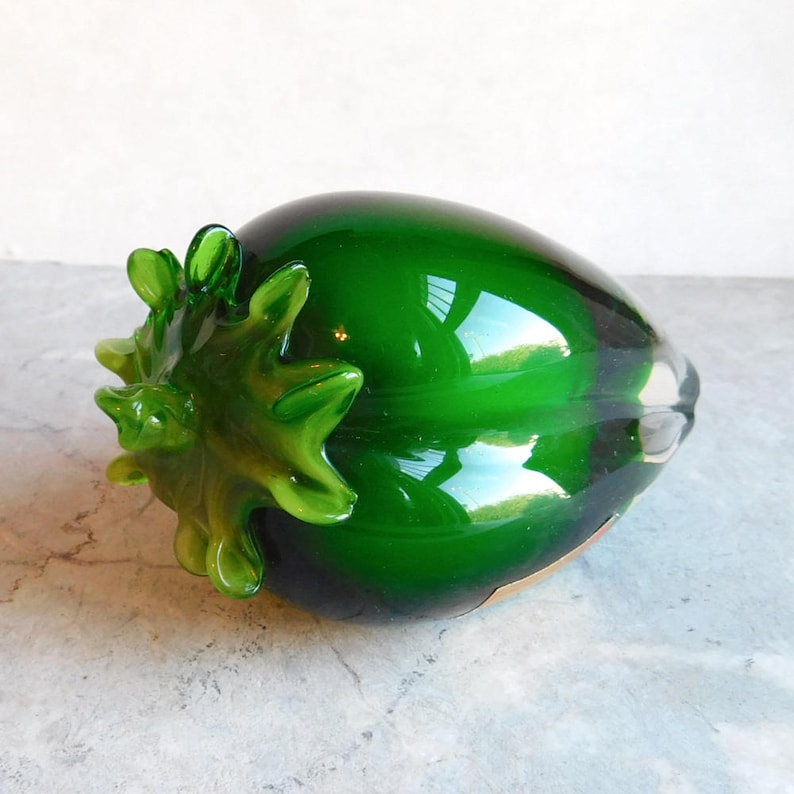 May include: A green glass sculpture of a large aubergine with a detailed, textured top.