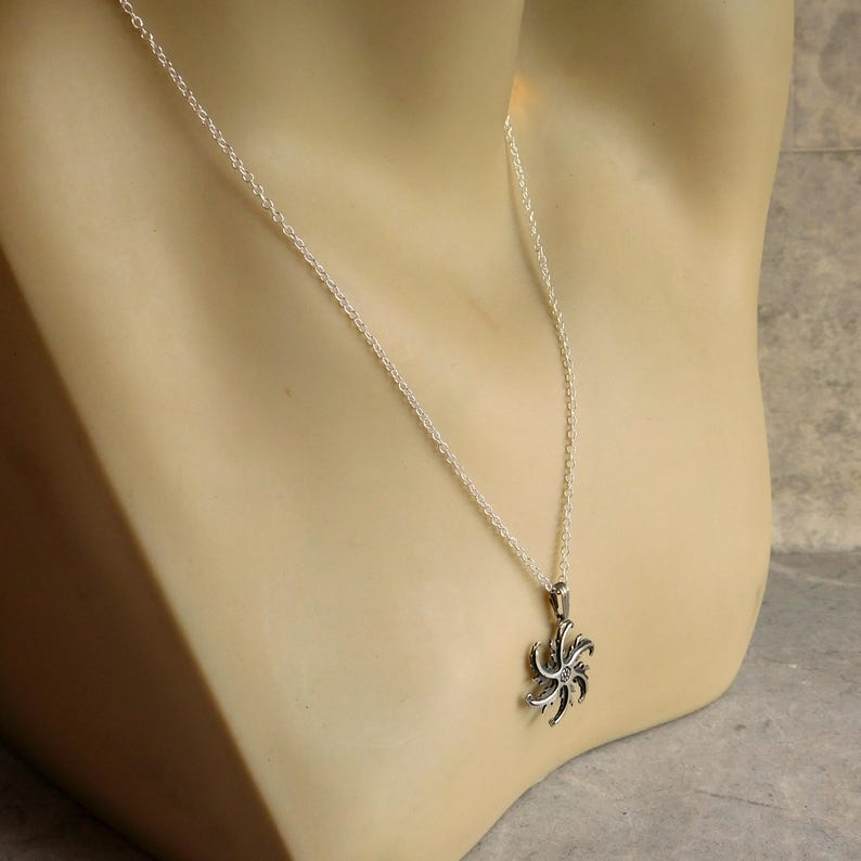 Op de afbeelding: Een zilveren ketting met een zilveren hanger met een gestileerd stervormig ontwerp.