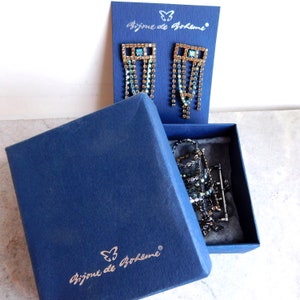 May include: A blue box with the text "Bijoux de Boh&egrave;me" and a butterfly logo. The box contains a pair of dangle earrings with a gold frame and blue and clear crystals. The earrings are in a clear plastic bag.