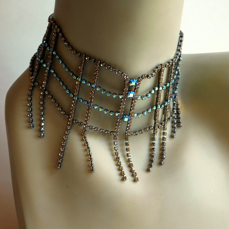 May include: A silver and blue rhinestone choker necklace with a geometric design and dangling fringe.