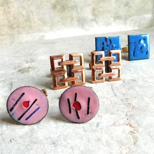 May include: A set of three ceramic mugs with a speckled, matte finish. The mugs are in shades of cream, light gray, and dark gray. Each mug has a simple, minimalist design and a rounded handle.