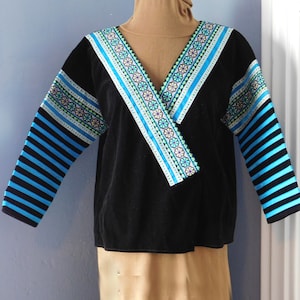 Può includere: Blusa in velluto nero con maniche a righe blu e bianche e un collo ricamato decorativo.