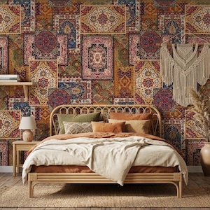 May include: A bedroom with a bohemian theme, featuring a bed with a rattan frame and a patterned rug. The wall is adorned with a patchwork of decorative panels in shades of red, blue, and gold. A macrame wall hanging and a vase with dried plants add to the decor.
