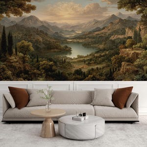 May include: A scenic landscape mural featuring a classical painting of a mountain range, lake, and forest. The artwork is displayed above a beige sofa with brown throw pillows, a wooden coffee table, and a round ottoman.