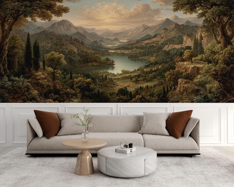 May include: A scenic landscape mural featuring a classical painting of a mountain range, lake, and forest. The artwork is displayed above a beige sofa with brown throw pillows, a wooden coffee table, and a round ottoman.