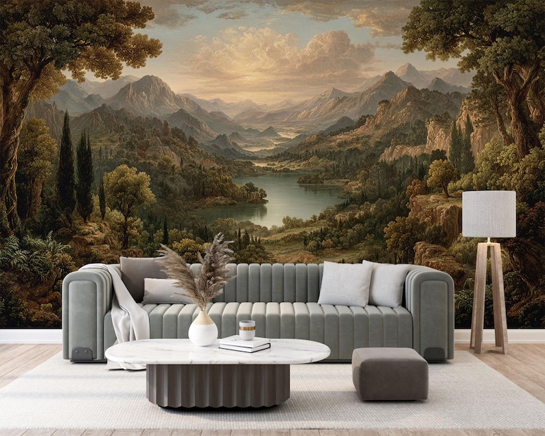 May include: A living room scene featuring a gray sofa, a white marble coffee table, and a matching ottoman. The backdrop is a large mural depicting a scenic landscape with mountains, a lake, and trees. A floor lamp with a white shade stands to the right.