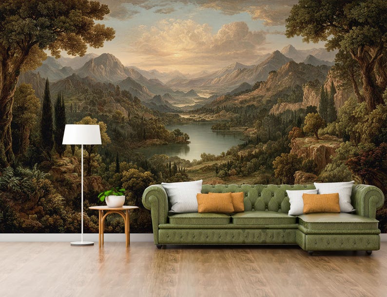 May include: A scenic mural depicting a mountain landscape with a lake, trees, and a sunset. A green sofa with white and orange pillows sits in front of the mural. A white floor lamp and a small table with a plant are also in the room.