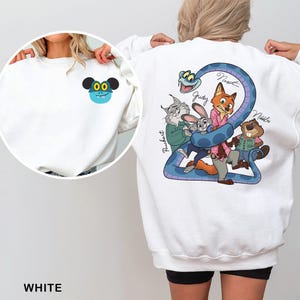 May include: White sweatshirt featuring a cartoon design on the front and back. The front has a blue and black cartoon character. The back has a blue snake with cartoon characters and names. The word "WHITE" is at the bottom.