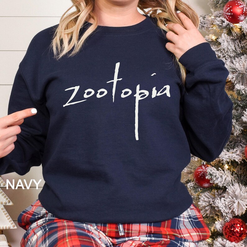 Puede incluir: Sudadera azul marino con la palabra "zootopia" en escritura blanca. La sudadera es de cuello redondo. La palabra "NAVY" est&aacute; impresa en blanco en la parte inferior izquierda de la imagen.