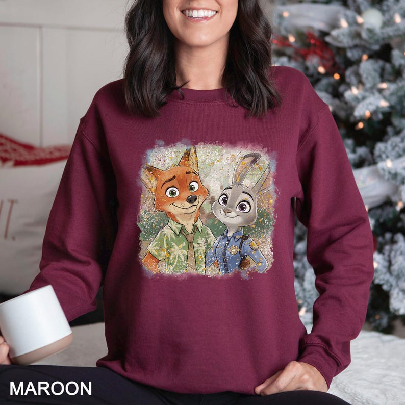 May include: Maroon sweatshirt featuring a cartoon image of a fox and a rabbit. The fox is wearing a green shirt, and the rabbit is in a blue police uniform. The word "MAROON" is printed at the bottom of the image.