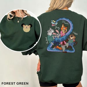 May include: Forest green sweatshirt featuring a cartoon illustration of characters from a movie. The front has a small mouse design. The back displays a blue snake with the number 2 and several characters. The sweatshirt is made of a soft material.