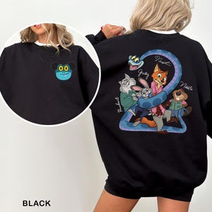 May include: Black sweatshirt featuring a cartoon design on the front and back. The front has a blue and yellow cartoon character. The back has a blue snake with cartoon characters and the names Judy, Nick, and Nibbles.