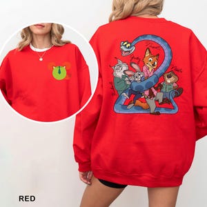 May include: A red sweatshirt featuring a cartoon graphic on the back with characters and the number 2. The front of the sweatshirt has a small cartoon graphic. The word "RED" is printed at the bottom.