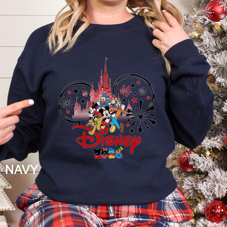 May include: Navy blue sweatshirt featuring a Disney design. The graphic includes a castle, Mickey Mouse and friends, fireworks, and the Disney logo in red. The text "2023" is below the logo. The word "NAVY" is printed on the bottom left.