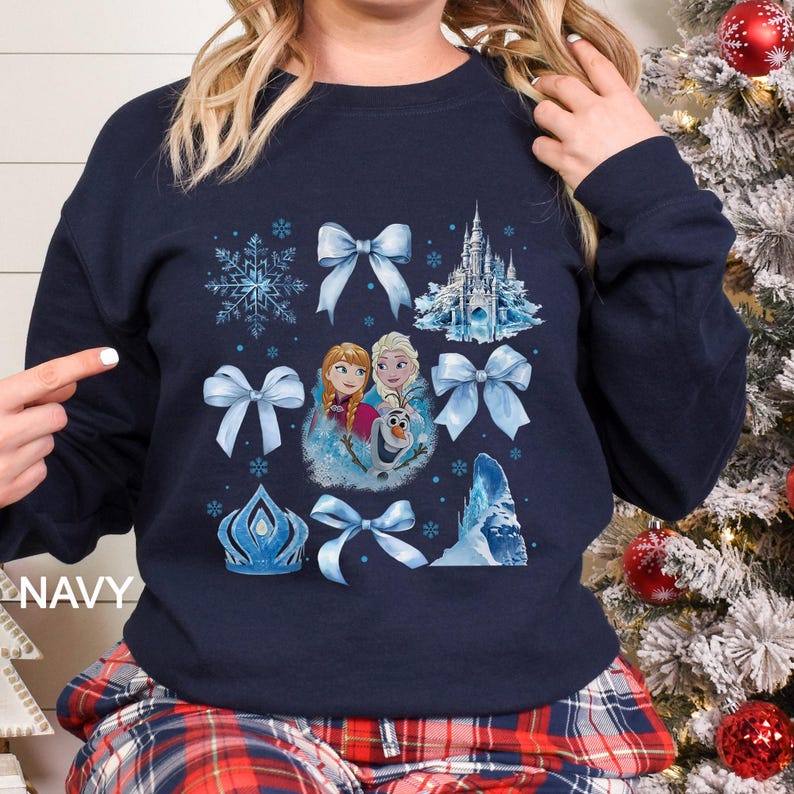 May include: Navy blue sweatshirt featuring a collage of light blue bows, snowflakes, a castle, and images of Anna, Elsa, and Olaf. The word "NAVY" is printed on the left side of the sweatshirt.