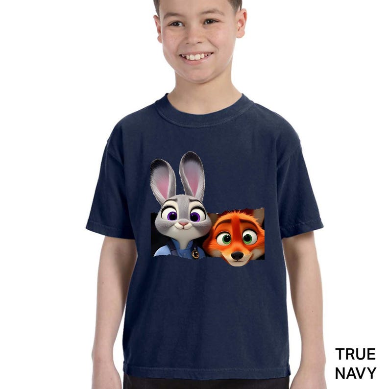 Pu&ograve; includere: T-shirt blu navy con una grafica di Judy Hopps e Nick Wilde di Zootopia. I personaggi dei cartoni animati sono in una cornice rettangolare. Il testo "TRUE NAVY" &egrave; stampato in basso a destra.