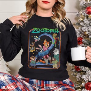 Puede incluir: Sudadera negra de cuello redondo con un gr&aacute;fico colorido de la pel&iacute;cula animada "Zootopia". El dise&ntilde;o incluye el t&iacute;tulo de la pel&iacute;cula y varios personajes. La sudadera se combina con un pantal&oacute;n de pijama a cuadros.