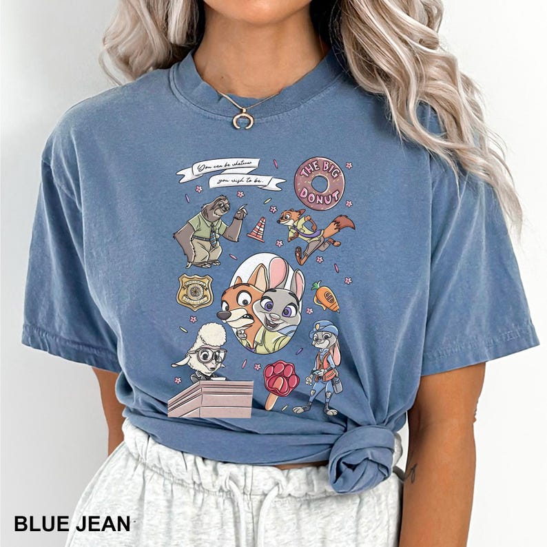 May include: Blue jean-colored t-shirt featuring a colorful graphic of characters from a popular animated movie. The design includes a donut, a carrot, and the text "You can be whatever you wish to be."